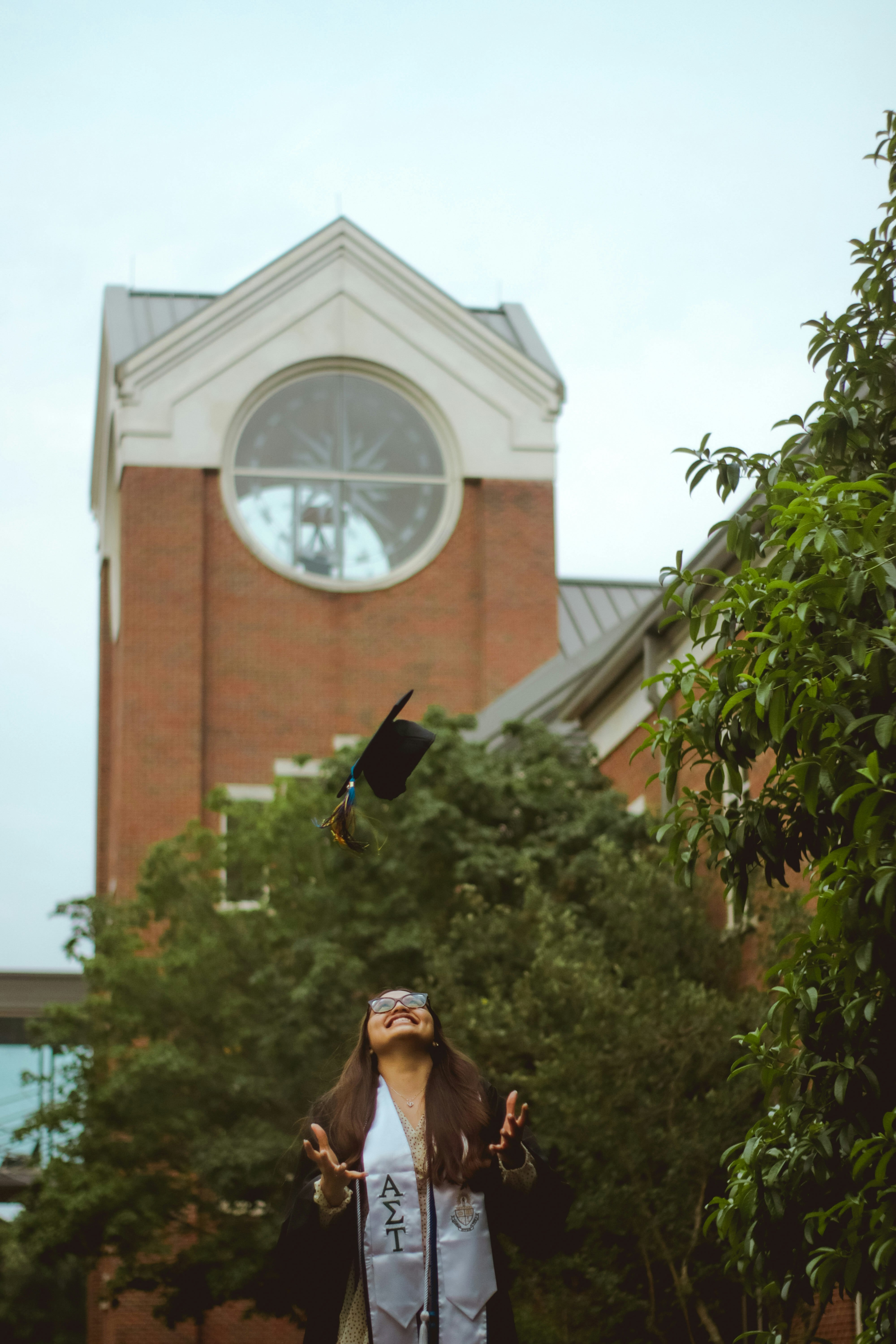 woman in black hat and brown coat standing near green tree during daytime